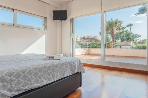 a bedroom with a bed and a large window at Villa Helios Aguadulce Almeria in Roquetas de Mar