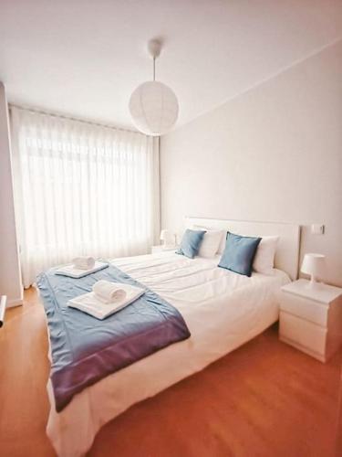 a bedroom with a large white bed with blue pillows at Alameda Apartments - Apartamento Moderno a 20 min do Porto in Trofa