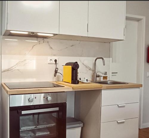 a kitchen with white cabinets and a sink and a counter at Alameda Apartments in Trofa