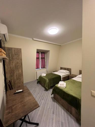 een hotelkamer met twee bedden en een tafel bij Rooms on Europe Square in Batoemi