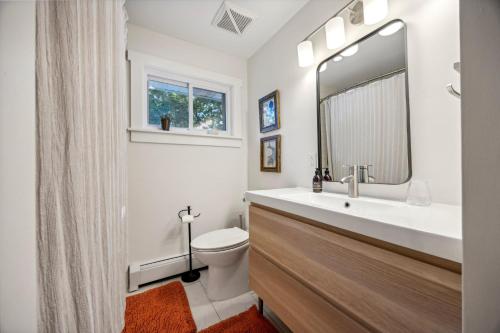 a bathroom with a sink and a toilet and a mirror at Modern Mid-Century Retreat in West Chester