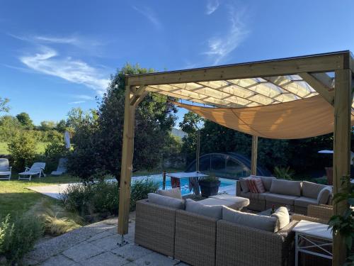 a pergola with couches and a couch under it at L'hébergerie sablotine in Chaillé-les-Marais