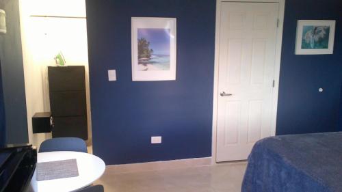 a bedroom with a blue wall with a bed and a table at E&J Boutique Residences in Sosúa