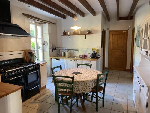 a kitchen with a table and chairs and a stove at L'hébergerie sablotine in Chaillé-les-Marais