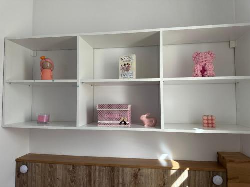 a room with white shelves with dolls and toys at Radiant BD Wejscie na kod in Gdynia