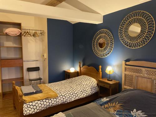 a bedroom with two beds and two mirrors on the wall at L'hébergerie sablotine in Chaillé-les-Marais
