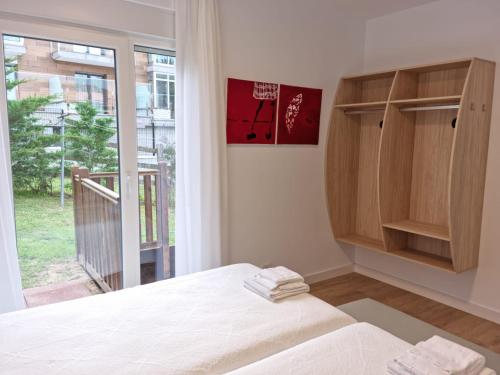 a bedroom with a bed and a large window at Playa Joyel Family Surf House in Noja