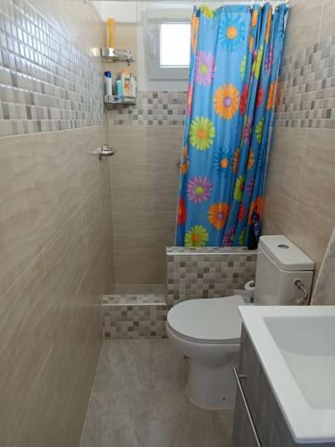 a bathroom with a toilet and a shower curtain at Santina's house in Posidhonía