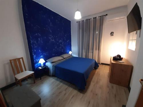 a bedroom with a blue bed and a table and chair at LAPILLI Holidays in San Giovanni la Punta