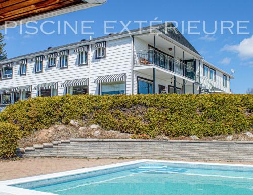 a building with a swimming pool in front of a house at Auberge de nos Aieux in Les Éboulements