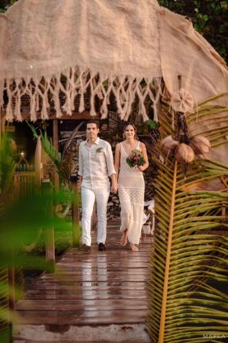 a bride and groom walking down a wooden bridge at Rosario EcoHotel in Isla Grande