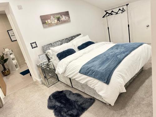 a bedroom with a bed with a blue blanket and pillows at JayGees luxury homes in Lower Gornal