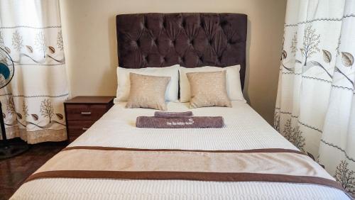 a bedroom with a large bed with a large headboard at Palm West in Bulawayo