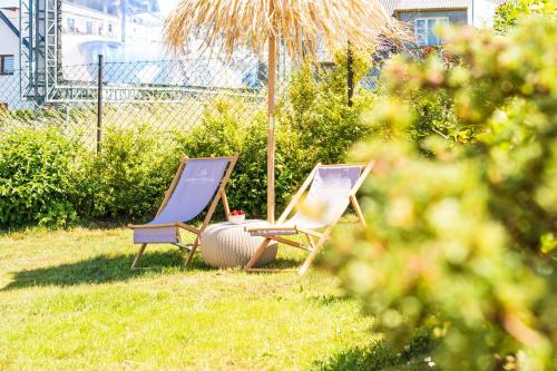 two lawn chairs and an umbrella in the grass at Remus House Apartments spokojny wypoczynek dla par, tylko pokoje 2-osobowe in Jastrzębia Góra