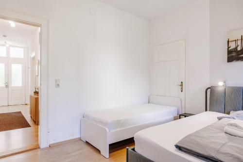 two beds in a room with white walls and wooden floors at Villa Plassenburg in Kulmbach