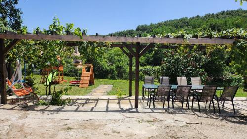 a table and chairs under a pergola with a playground at Къща за гости Роден Балкан in Karalite