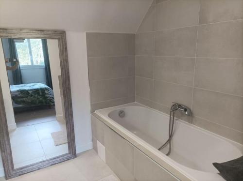 une salle de bain avec une baignoire et un miroir dans l'établissement Maison chaleureuse en bord de mer, à Moëlan-sur-Mer