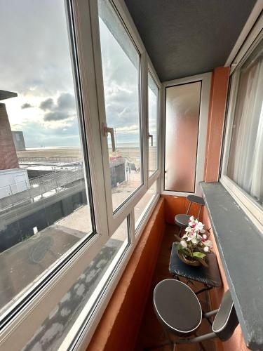 une chambre avec deux chaises, une table et deux fenêtres dans l'établissement Appartement avec vue sur mer, à Dunkerque