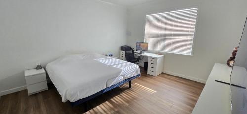 a bedroom with a bed and a desk and a window at Rent W Palm Beach in West Palm Beach