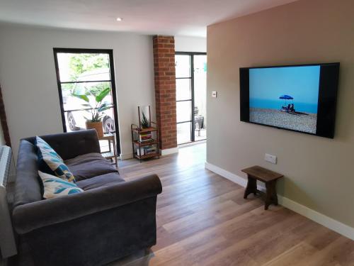 a living room with a couch and a flat screen tv at Hastings Casita, 'little house' self contained garden lodge, close to town and seafront in Hastings