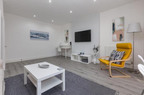 a living room with a yellow chair and a table at Lytham St Annes Luxury Apartment - No 2 Tides Reach in Lytham St Annes