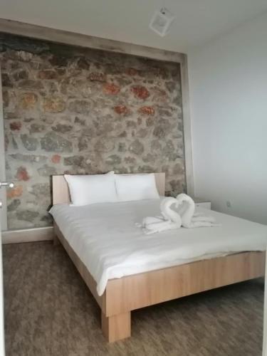 a bedroom with a bed with a stone wall at CHRIS sopo in Elshani