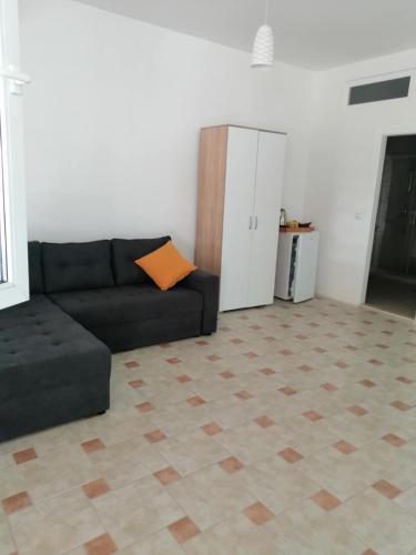 a living room with a black couch with an orange pillow at CHRIS sopo in Elshani