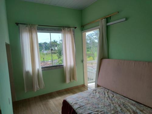 una camera da letto verde con un letto e una finestra di Praia do Ervino SC a São Francisco do Sul
