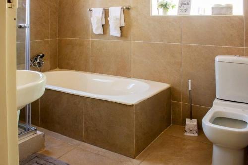 a bathroom with a tub and a toilet and a sink at Little Oasis Self Catering Cottage in Harare