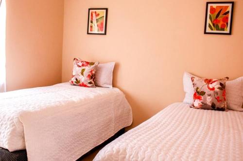 two beds in a room with pink walls at Little Oasis Self Catering Cottage in Harare
