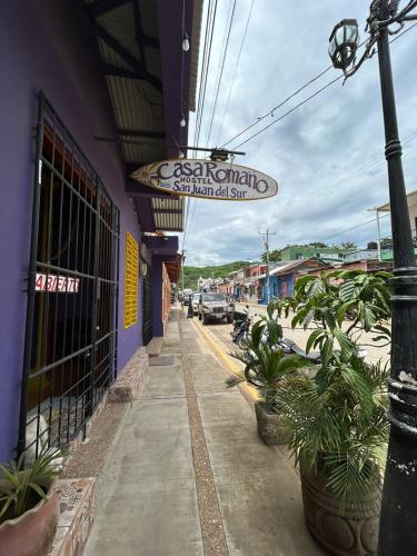 a building with a sign on the side of a street at Casa Romano Hostel in San Juan del Sur