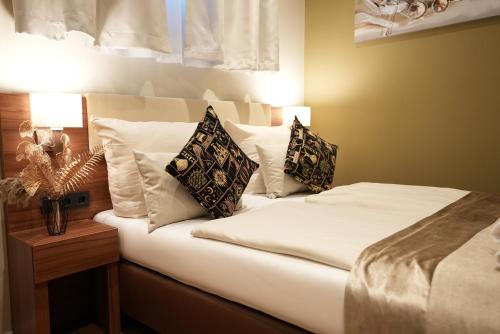 a bedroom with a bed with white sheets and pillows at Hotel Attaché an der Messe in Frankfurt/Main