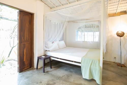 a bed with a canopy in a room with a window at Villa Ostello in Paripueira
