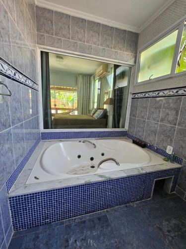 a bathroom with a large tub with a mirror at Casarão no Recanto de Itaipuaçu in Maricá