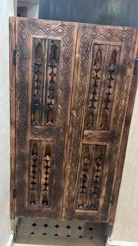a wooden cabinet filled with lots of wine bottles at Riad Rkiya with Courtyard in Tiznit
