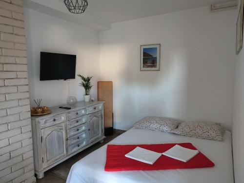 Un dormitorio con una cama y una cómoda con televisión. en Apartman Noemi, en Jadranovo