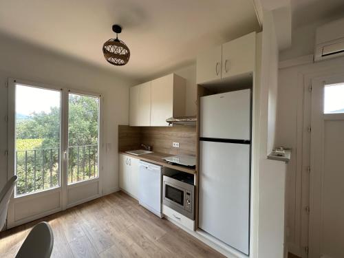 une cuisine avec un réfrigérateur blanc et une fenêtre dans l'établissement Magnifique appartement T3 rénové avec goût au coeur des vignes, à Cogolin