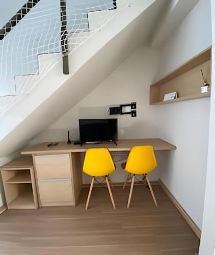 a room with a desk and two yellow chairs at Lofts Umuarama Residence in Uberlândia