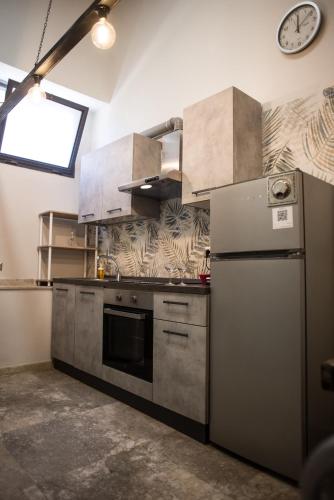 a kitchen with a refrigerator and a clock on the wall at Sweet Loft Ostia in Lido di Ostia