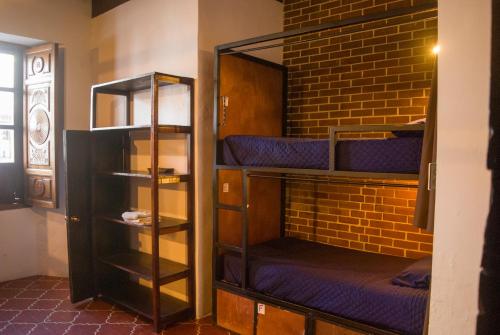 a room with three bunk beds and a brick wall at Tzunun Hostel in Antigua Guatemala