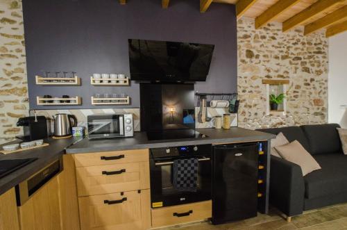 a kitchen with a stove and a couch in a room at Le Petit Candie in Maisoncelles-en-Brie
