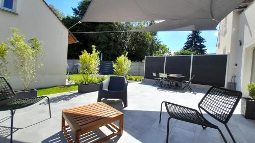 a patio with a table and chairs and an umbrella at Le Petit Candie in Maisoncelles-en-Brie