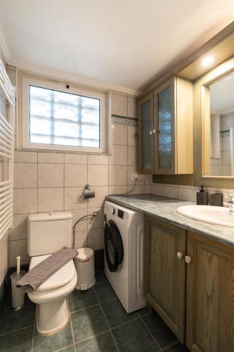 a bathroom with a toilet and a sink and a washing machine at La Dimora in Lixouri