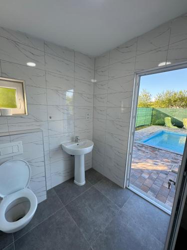 a bathroom with a toilet and a sink and a pool at Crystal pool in Bihać