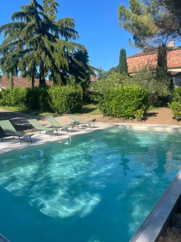 - une piscine avec des chaises et un arbre dans l'établissement Grande Maison de famille, 12pers, Piscine privée, Vallée du Lot & Bastides, à Lédat