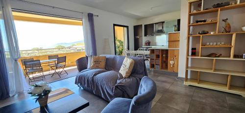 un salon avec un canapé et une grande fenêtre dans l'établissement T3 de standing Vigna Majo vue mer imprenable, à Propriano
