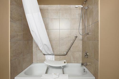 a bathroom with a tub and a shower with a toilet at Grande Cache Inn & Suites in Grande Cache