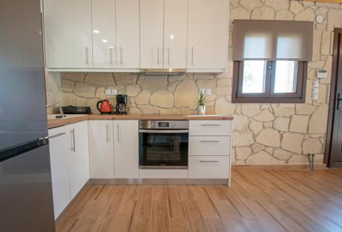 eine Küche mit weißen Schränken und einer Steinmauer in der Unterkunft Ikarion Village Home by RentalsPro- Fourka Halkidiki in Fourka
