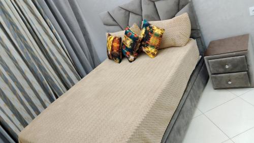 a bed with three pillows on it with a curtain at حي المطار إقامة العالية أمام حمامات العالية in Tazrout