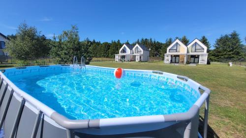 Una piscina con una bola roja en un patio con casas. en Domki Całoroczne nad Morzem Kraina Bałtyku, en Przewłoka